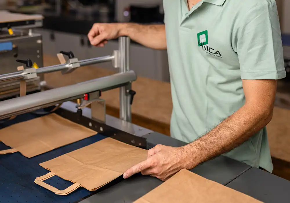 Operatore Unica Packaging durante il controllo qualità di shopper in carta alimentare personalizzate, realizzate con processi certificati e materiali sostenibili.