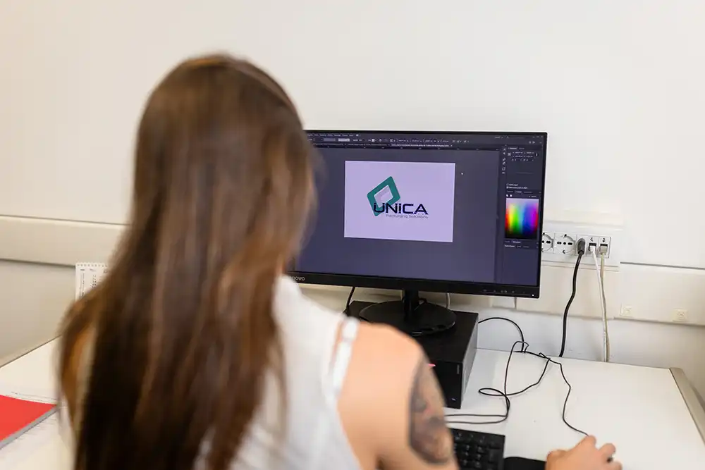 Grafica al computer al lavoro sul logo UNICA in un software di design, simbolo di progettazione su misura, rendering grafico e personalizzazione del packaging.