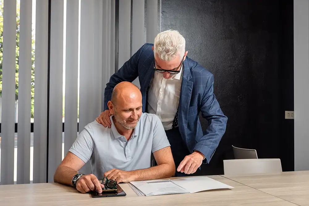 Due professionisti discutono insieme una proposta commerciale in ufficio, rappresentando collaborazione, rete vendita e consulenza al cliente.